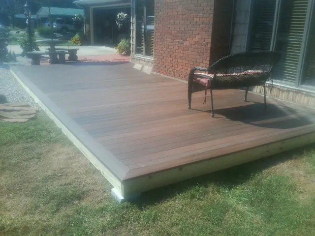 New wood deck and wicker chair beside a brick house in Harrison